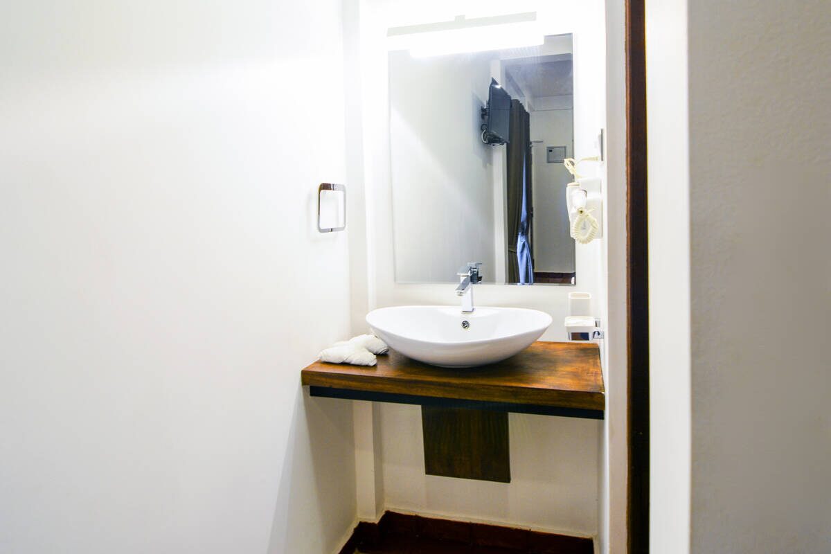 A vessel sink set on a warm wood vanity in an Arana bathroom
