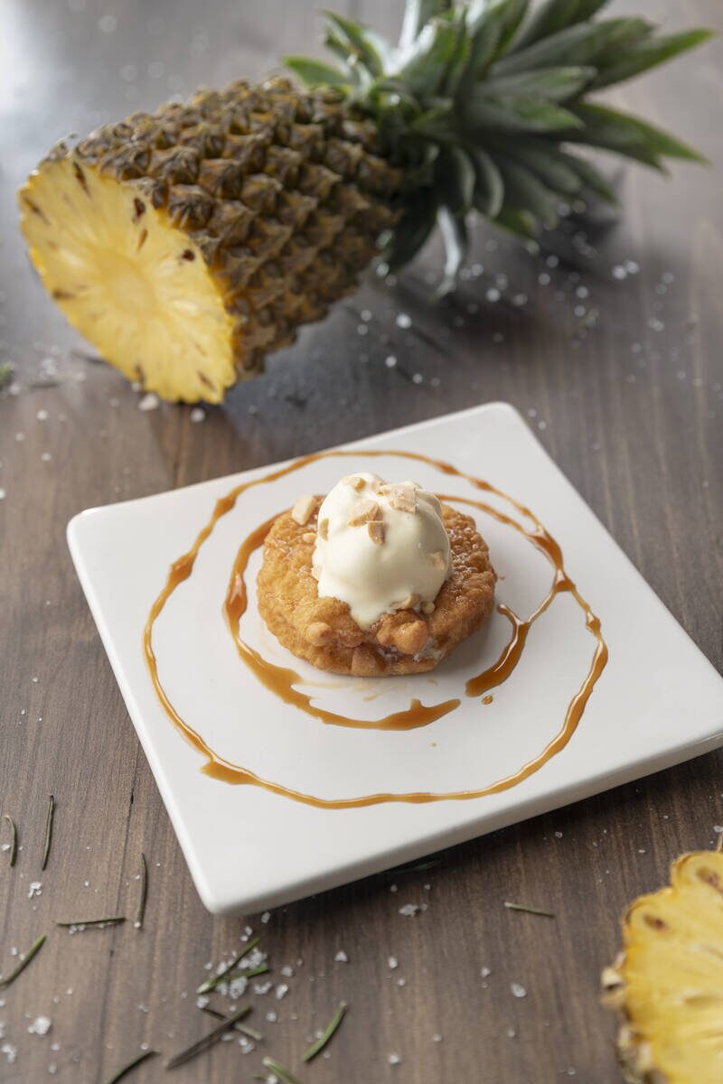 A pineapple fritter dessert on a white plate at Arana