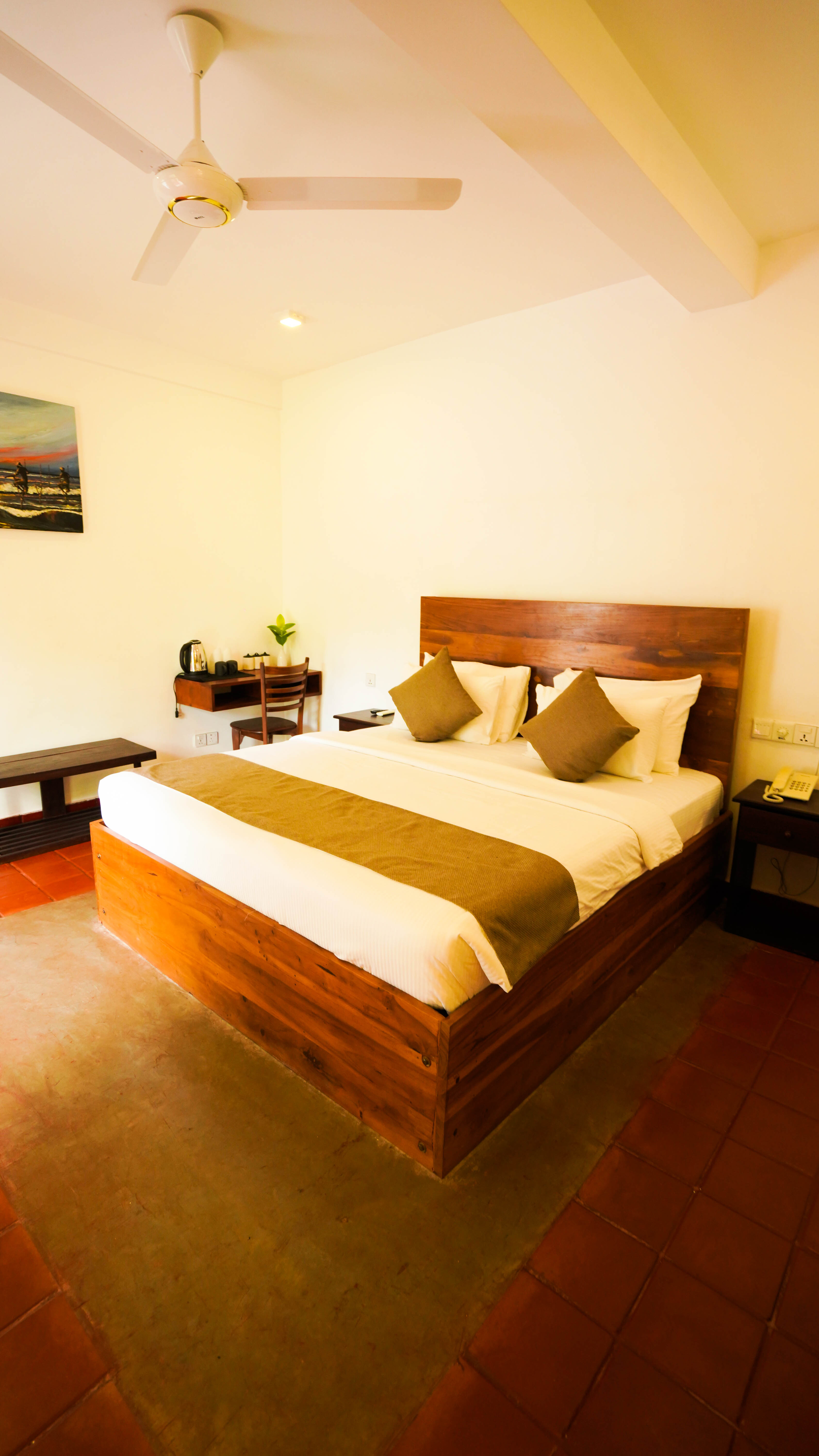 Detail of a bed at Arana with a framed painting mounted on the wall above it